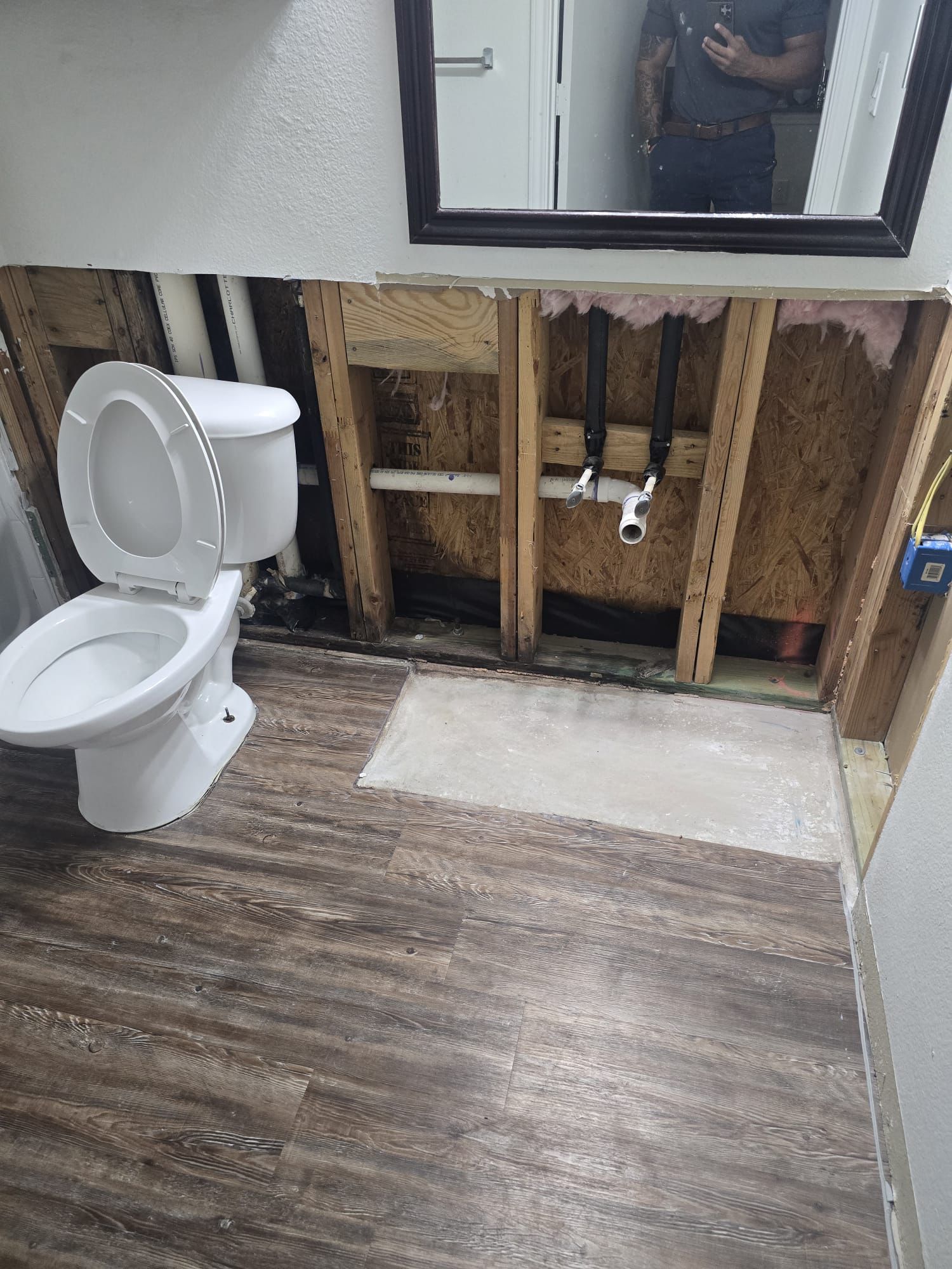 Before: bathroom with exposed wall framing and plumbing